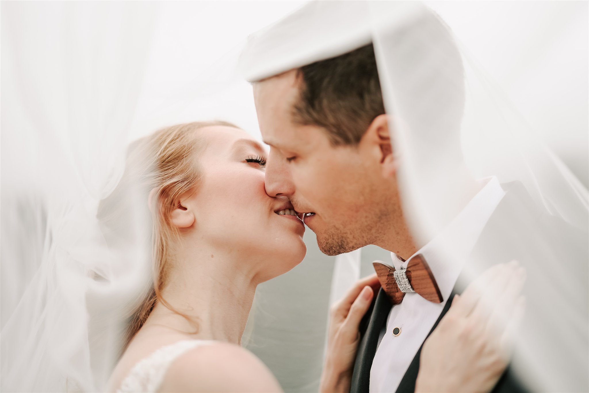 bride and groom sharing a kiss under the bride's veil at their American Creek Lodge Wedding