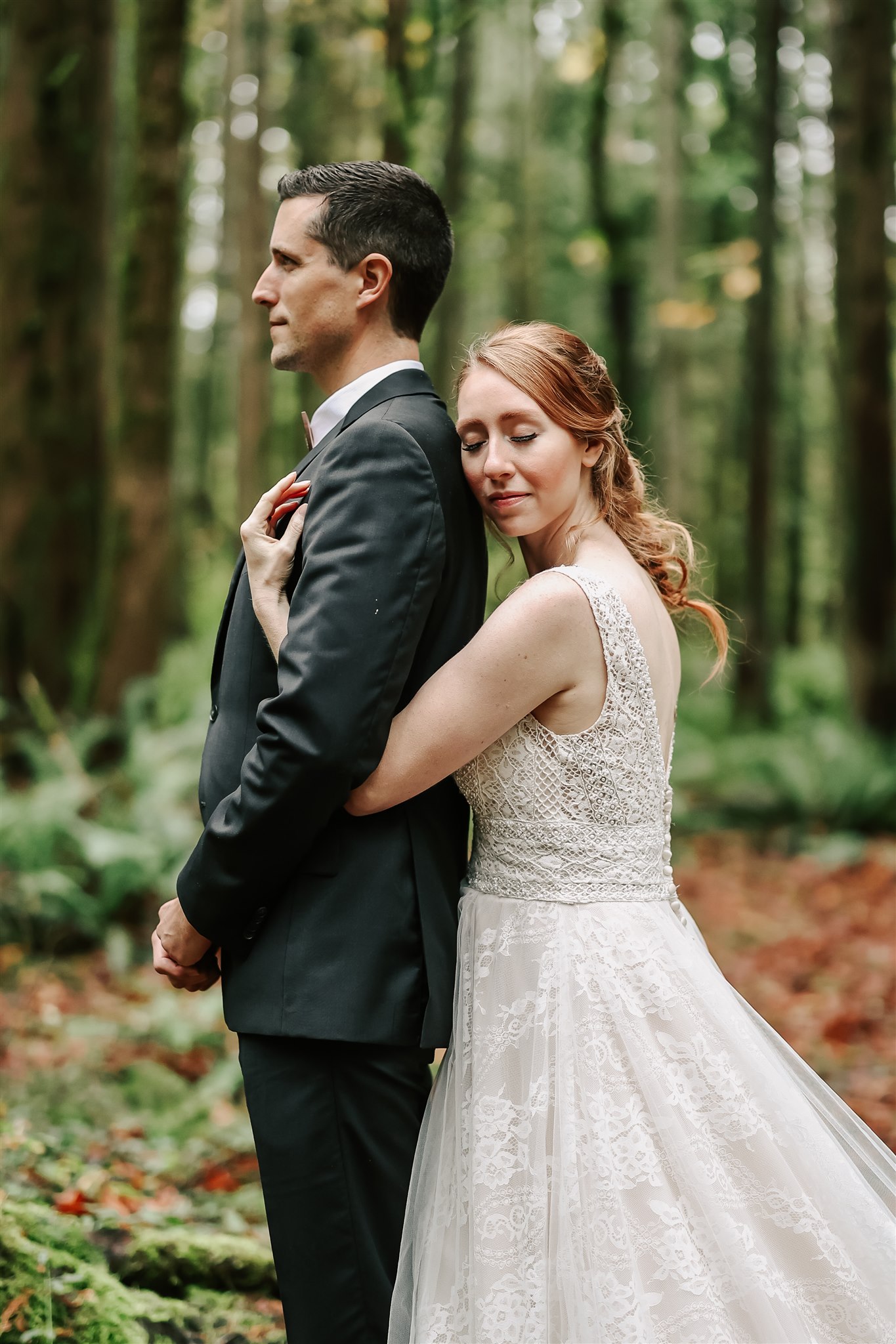 bride hugging her groom from behind in a forest