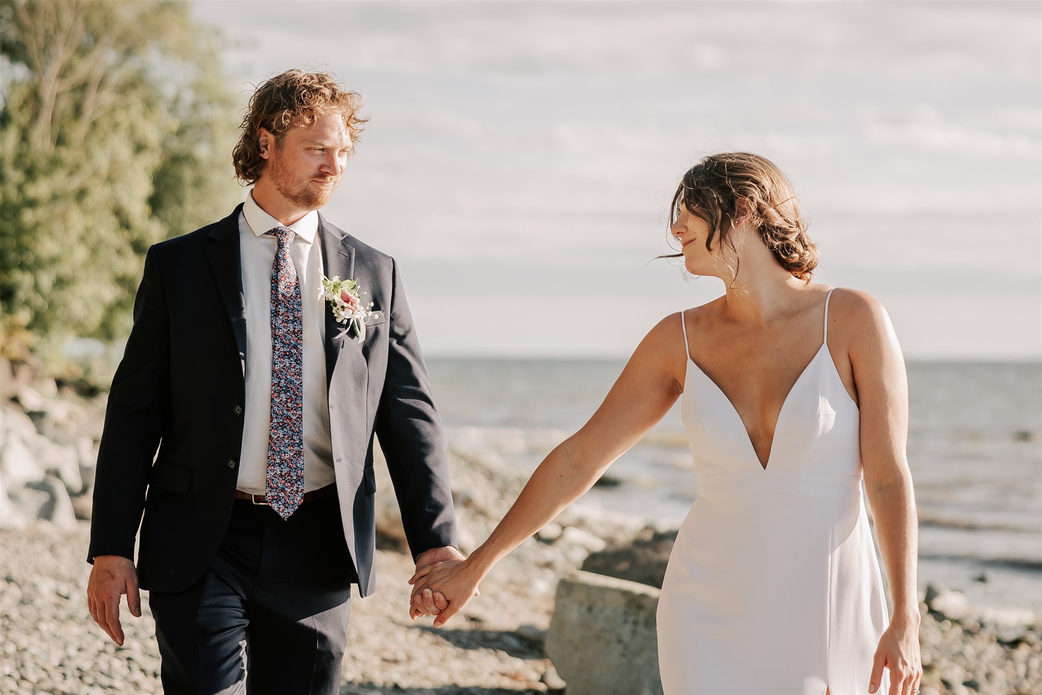 bride and groom walking hand in hand along the beach